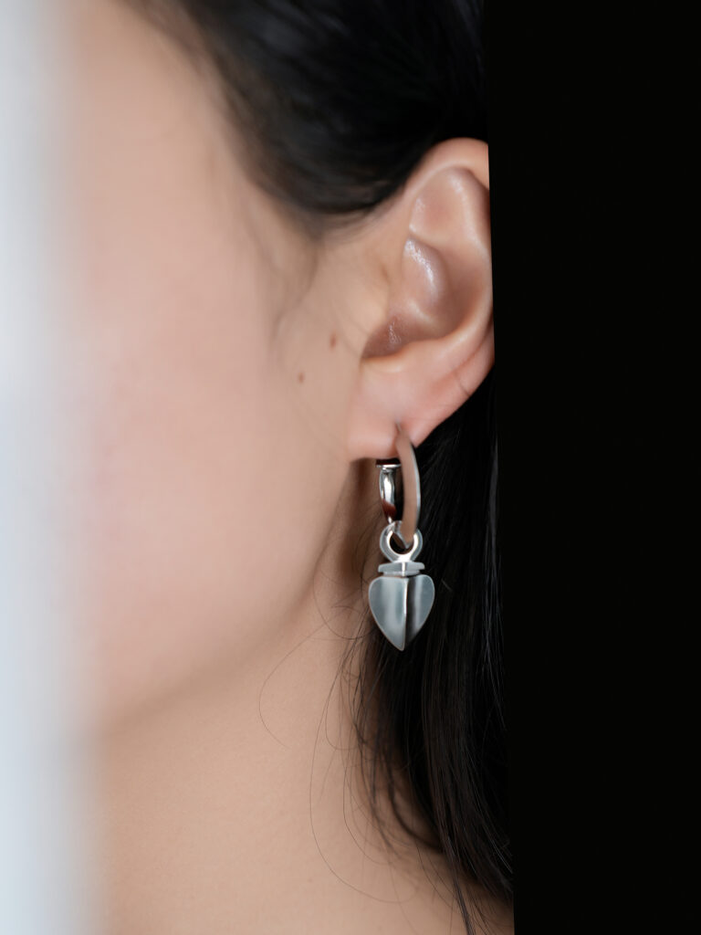 Brave Heart collection earrings: Silver metal hoop with a removable geometric heart charm, showcasing bold lines to express personalized style.