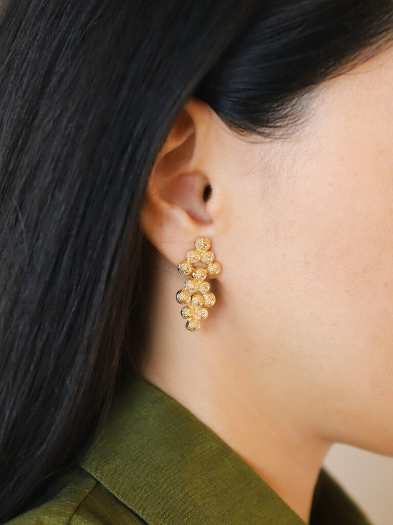 Gold grape cluster earrings with matte textured finish and 3D linked ball craftsmanship, as seen on model